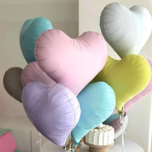 Pastel-colored heart-shaped balloons on a stand against a neutral background