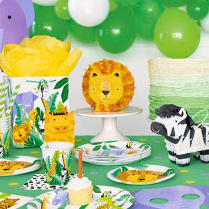 Jungle-themed party setup with lion cake, zebra, and other decorations on a table.