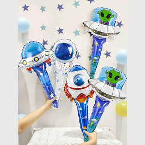 Space-themed balloons including UFOs, planets, and aliens held by a person against a light background.