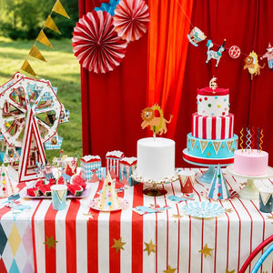 Carnival-themed party setup with cake, decorations, and tableware on a red and white striped tablecloth.