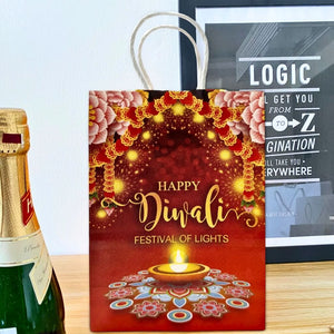 Red 'Happy Diwali' gift bag with a bottle of champagne on a wooden surface.