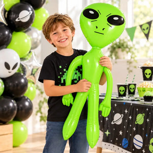 Person posing with a green inflatable alien at a science fiction-themed birthday photo booth