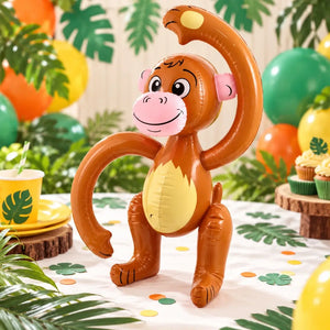 Inflatable brown monkey displayed at a jungle-themed birthday party with green balloons and tropical leaf decorations