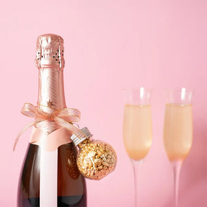 Glass JOY bauble filled with gold sprinkles and a hanging cord on bottle