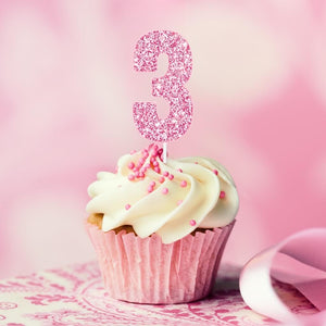 Pink glitter number birthday numeral cake topper inserted on cupcake