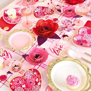 Decorative table setting with floral plates, pink roses, and 'love' text on a checkered tablecloth.
