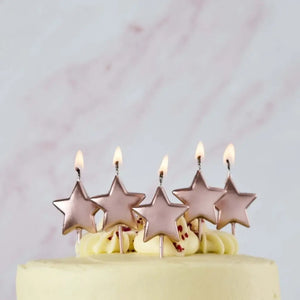 Five rose gold metallic star birthday candles on a celebration cake