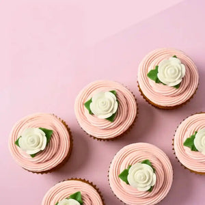 White edible rose cake decorations with green leaves