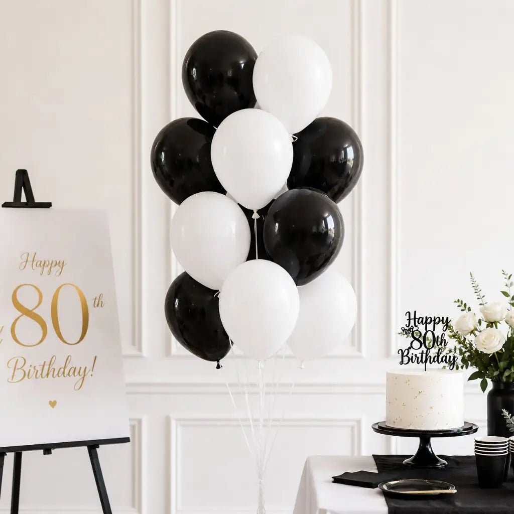 Black and white birthday party setup with balloons, cake, and decorations.