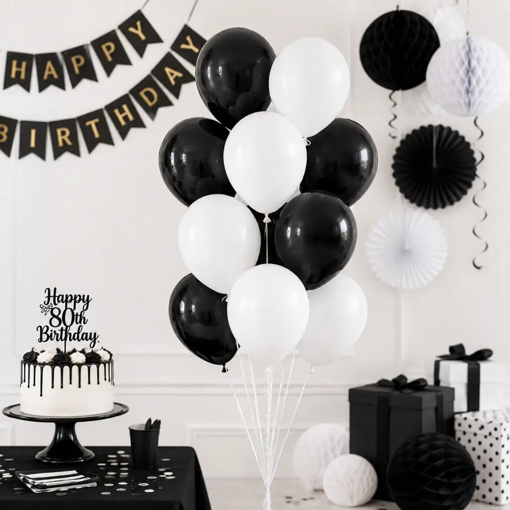 Black and white birthday party setup with balloons, cake, and decorations.