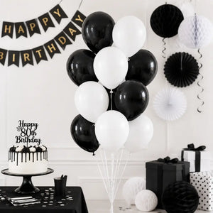 Black and white birthday party setup with balloons, cake, and decorations.