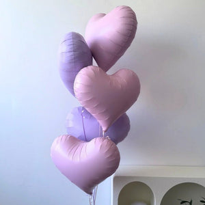 Heart-shaped balloons in purple and pink on a light background