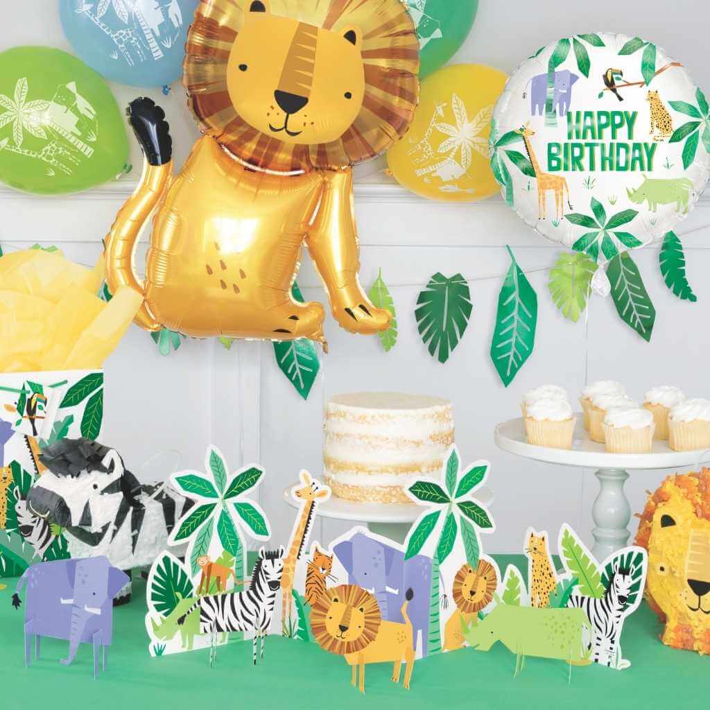 Jungle-themed birthday party decorations with balloons, cake, and animal cutouts.