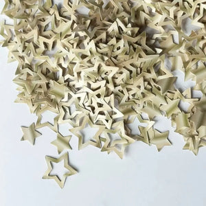 Light champagne star confetti scattered across a white party table