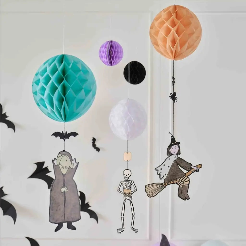 Witch, skeleton and Dracula hanging beneath honeycomb paper balls