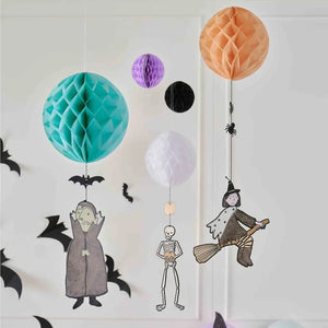 Witch, skeleton and Dracula hanging beneath honeycomb paper balls