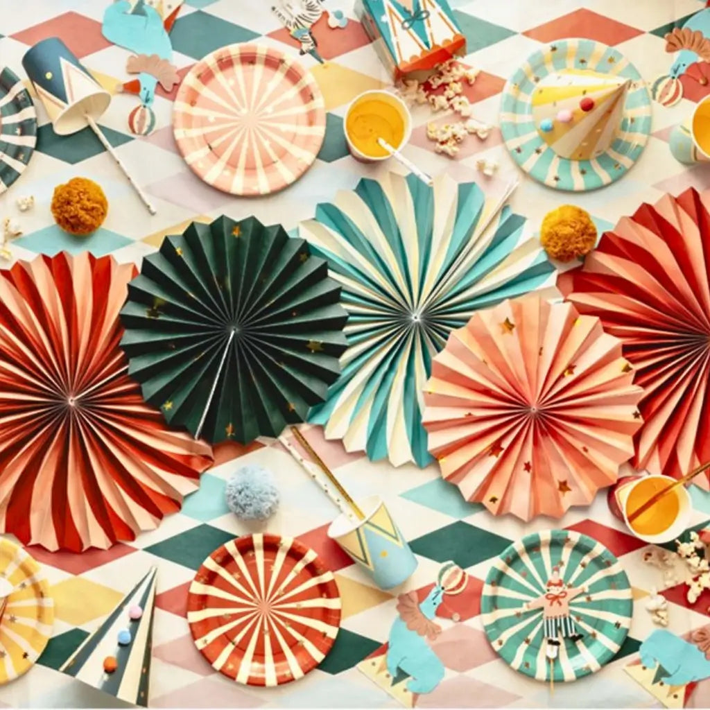 Colorful circus paper fans and party decorations on a patterned surface