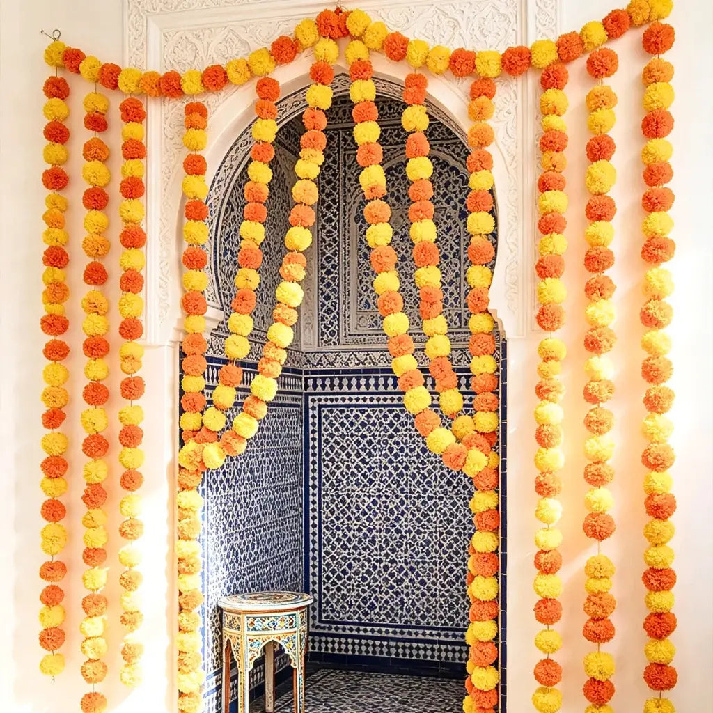 Yellow and orange pom pom garland hanging across a doorway for a Diwali celebration