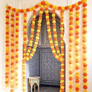 Yellow and orange pom pom garland hanging across a doorway for a Diwali celebration