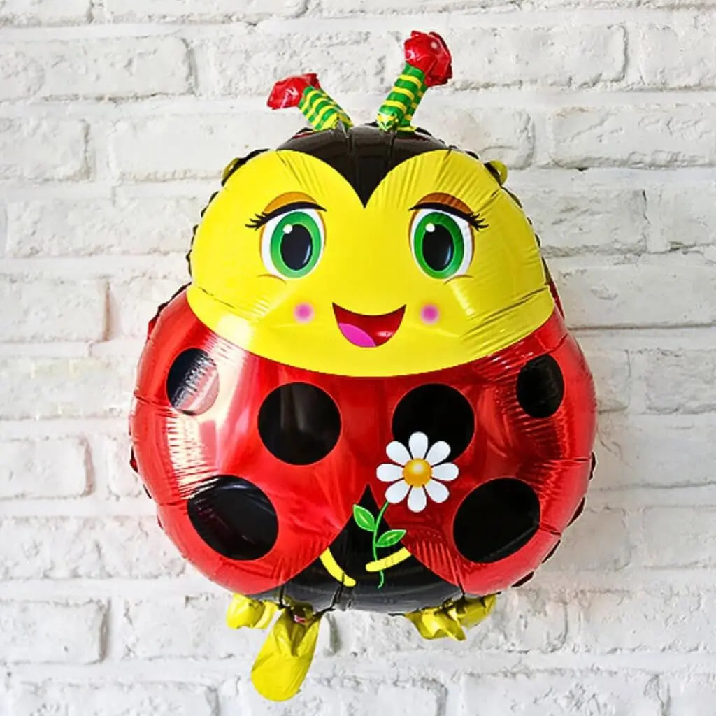 Colourful ladybug-shaped balloon against a white brick wall background