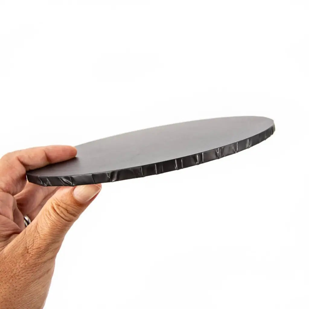 Side view of a rigid matte black masonite cake board showing its wrapped edge and flat surface