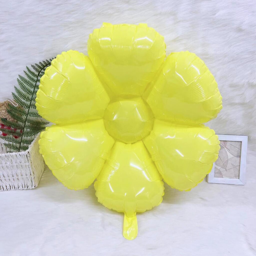 Yellow flower-shaped balloon on a white surface with a light gray textured background