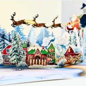 Snowy Village with Flying Santa on Sleigh & Reindeers Pop Card