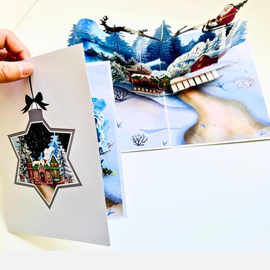 Snowy Village with Flying Santa on Sleigh & Reindeers Pop Card